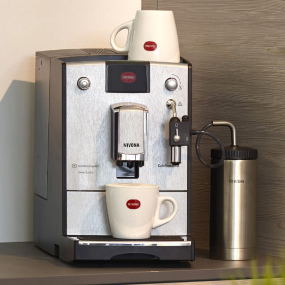 Kaffeevollautomat der Marke Nivona mit Kaffeetassen und einem Milchbehälter